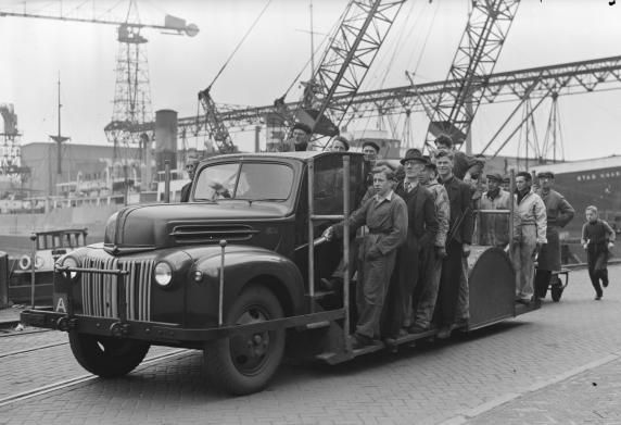 Een opstapwagen vol mensen op de waterkant.
