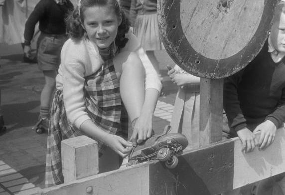 Een meisje strikt de veters van haar rolschaatsen, 1955.