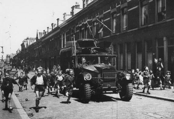 Een geallieerde militaire geluidswagen rijdt in een straat in de wijk Kralingen.