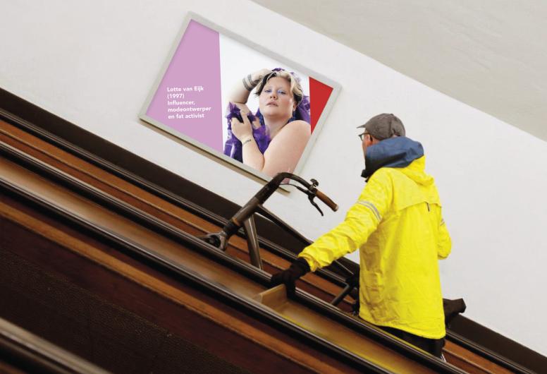 Man op fiets de roltrap op in de fietstunnel kijkend naar een afbeelding van een vrouw op de muur