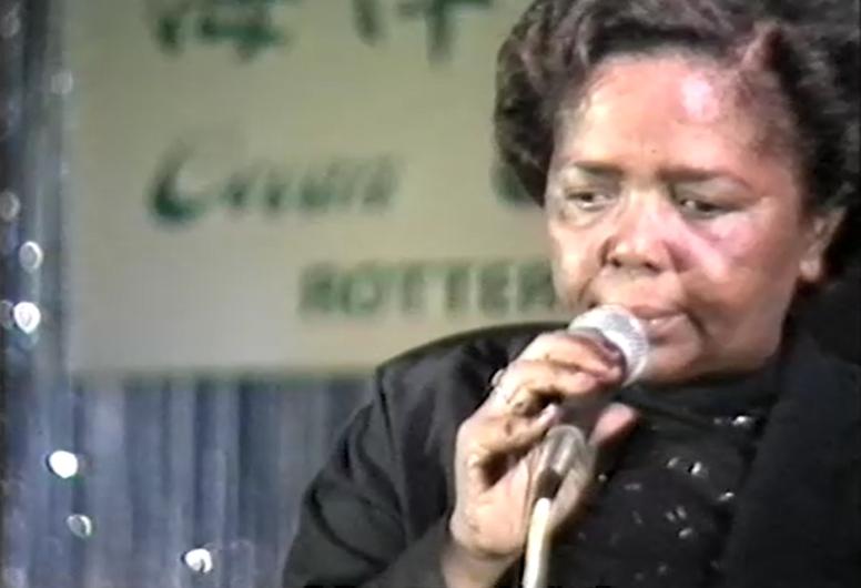 Een screenshot van de uitzending van TV Mozaïek van 27 oktober 1988. Cesária Évoria is te zien met microfoon tijdens het concert in de Nieuwe Ocean Paradise.