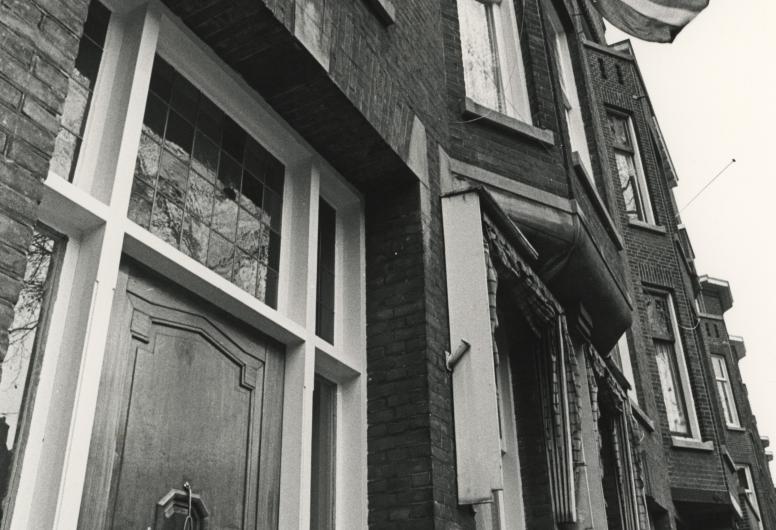 Zwart foto van herenhuis met Surinaamse vlag opgestoken