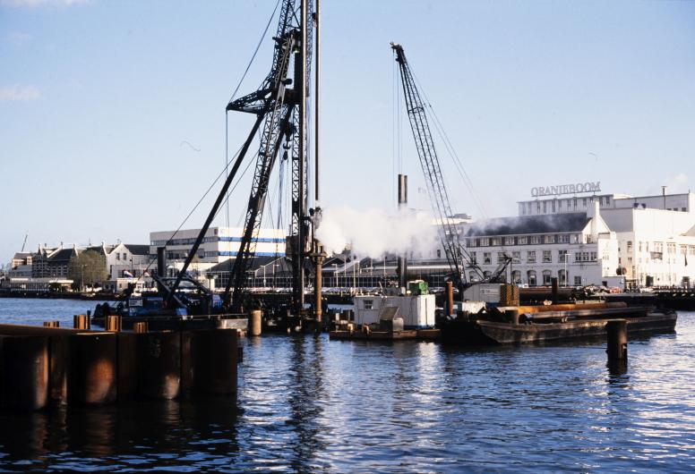 Bouwwerkzaamheden aan de spoortunnel in de Koningshaven als gezien vanaf de Prins Hendrikkade. 