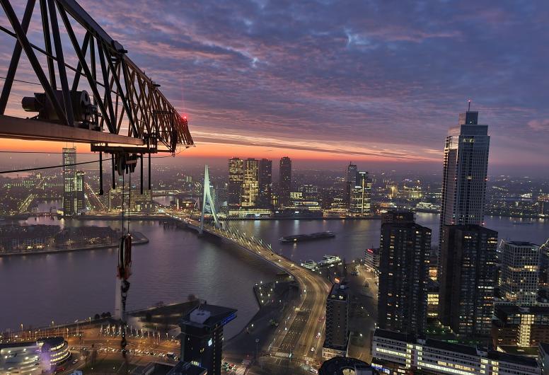 Luchtfoto in zuidelijke richting na zonsondergang over de Nieuwe Maas vanuit de werkbak van een kraan tijdens de bouw van de Cooltoren.