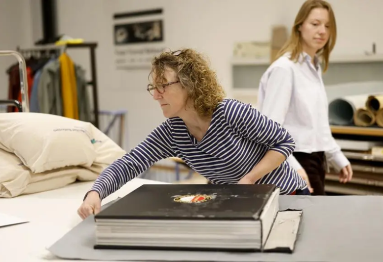 medewerker van het archief op de foto voorovergebogen over een groot boek