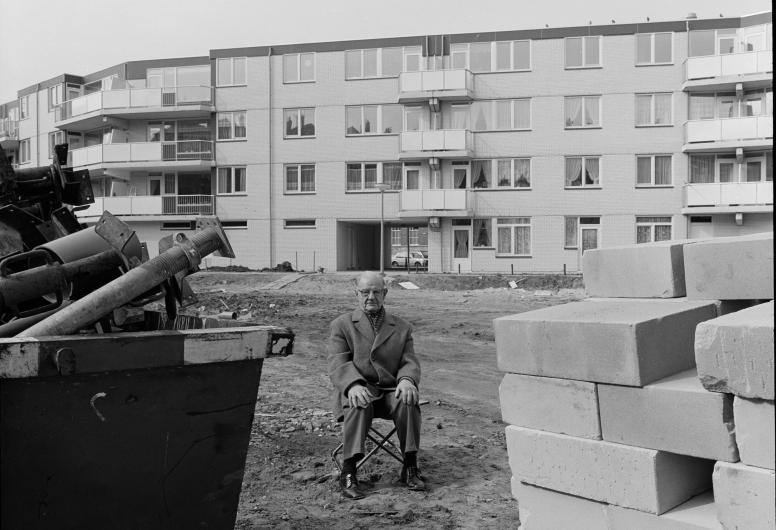 Man met sigaar poseert voor nieuw appartementencomplex, 1983