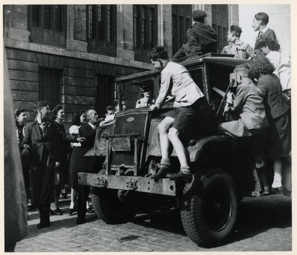 Mensen op en rondom een legertruck in mei 1945