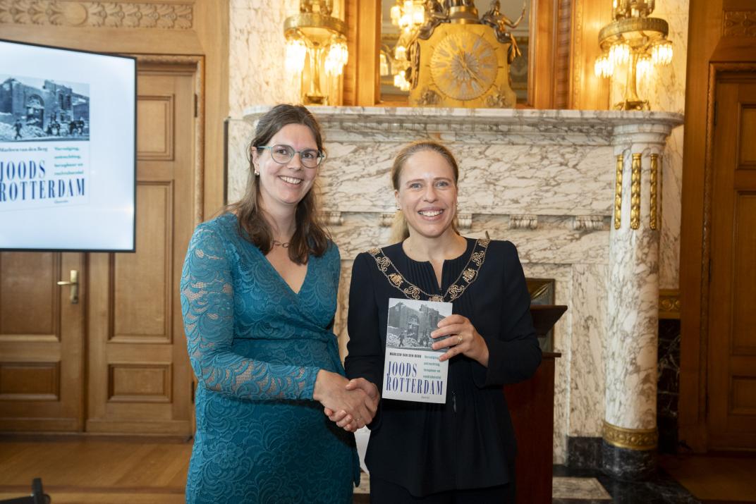Twee vrouwen die elkaar de hand geven terwijl de rechter een boek laat zien