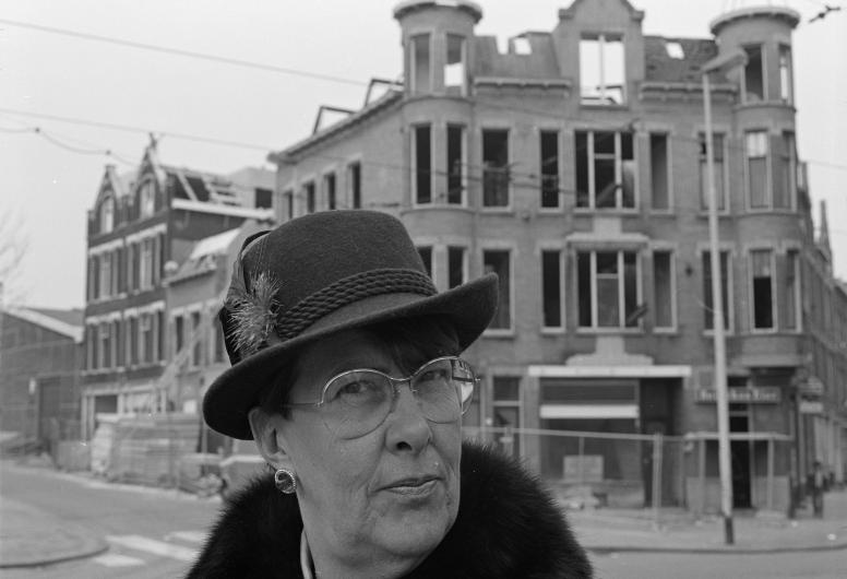 Een vrouw met hoed staat voor een pand aan de Zaagmolendrift dat gerenoveerd wordt. De foto is gemaakt voor het boek 'Die stad komt nooit af'.