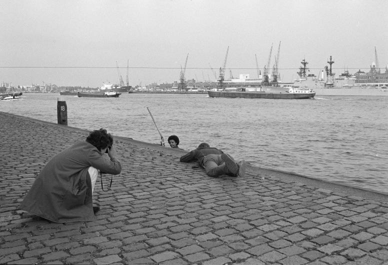 Fotograaf Eric van der Schalie ligt op de Wiilemskade om een model te fotograferen voor het boek 'Die stad komt nooit af'.