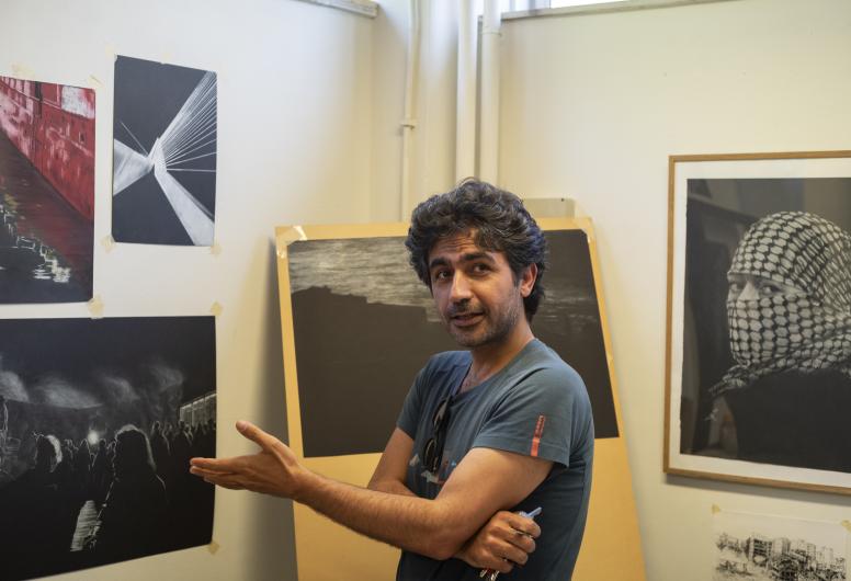 Foto van Peyman Fazeli, stadstekenaar 2026, staand in een ruimte met zijn tekeningen