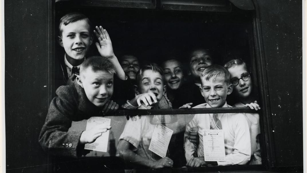 Kinderen hangend uit het raam van een trein in het station Delftse Poort