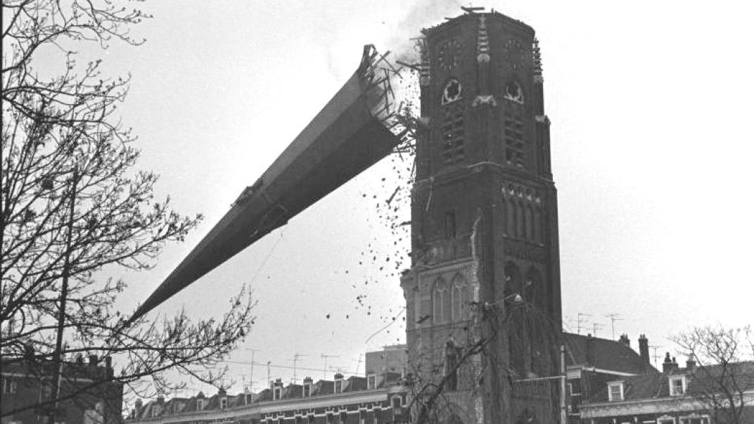 foto van een kerktoren dat naar beneden valt tijdens de sloop van het gebouw