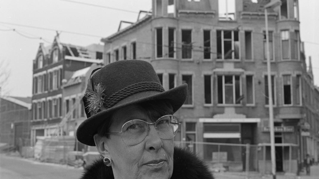 Een vrouw met hoed staat voor een pand aan de Zaagmolendrift dat gerenoveerd wordt. De foto is gemaakt voor het boek 'Die stad komt nooit af'.