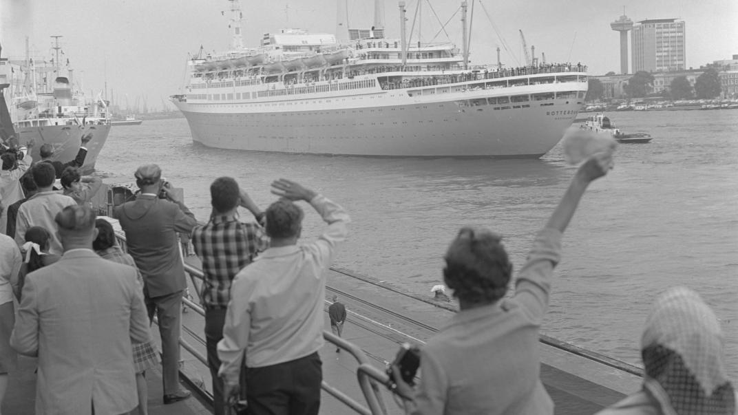 Zwaaiende mensen op de kade van de Holland Amerika-Lijn-vertrekhallen aan de Wilhelminakade. De ss Rotterdam vaart uit, 1968.Nummer uit collectie: NL-RtSA_4121_24162-1-14